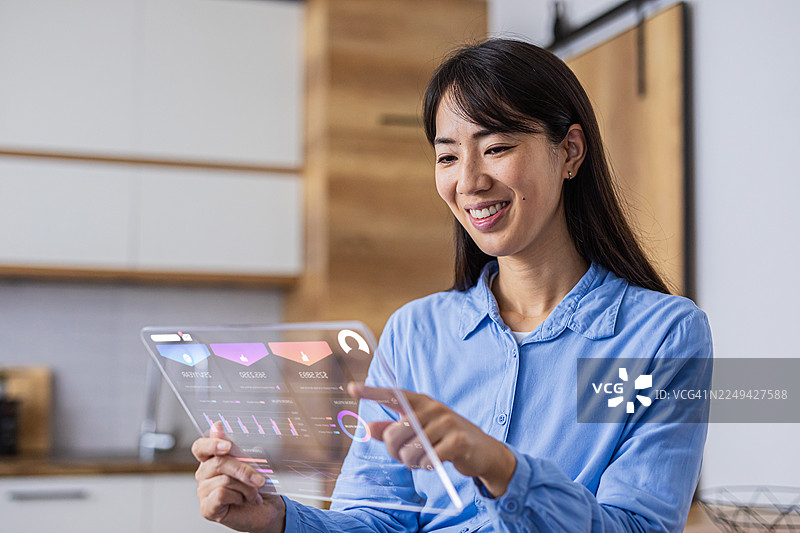 女性使用未来感十足的透明平板控制智能家居系统图片素材
