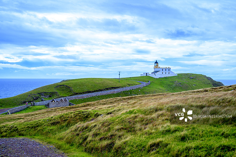 英国斯托尔，一座灯塔坐落在绿色的山丘上，俯瞰着海面，天空布满云彩，景色优美图片素材