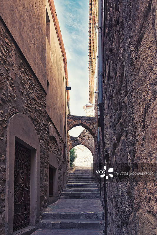 西班牙蒙特布兰克古老城镇中狭窄的石巷，有古老的拱门和向上的台阶图片素材