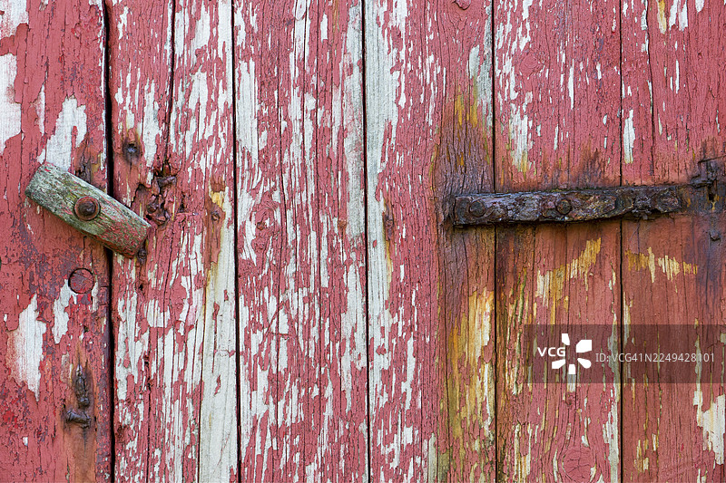 法罗群岛米基内斯岛一扇老旧的木门，红漆剥落，合页生锈图片素材
