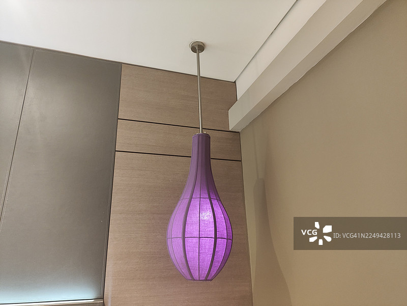 现代紫色吊灯悬挂在天花板上，照亮了现代室内空间图片素材
