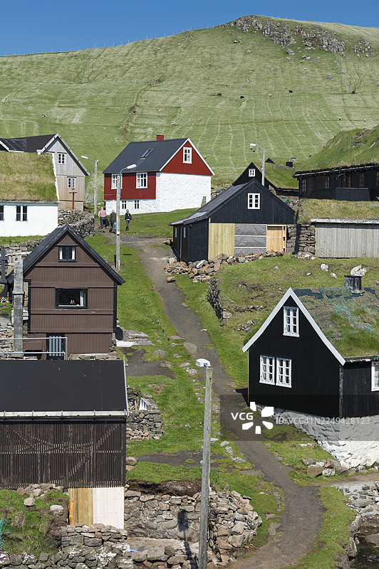 白色窗框的传统房屋，建在石头地基上的法罗传统木结构建筑，有草皮屋顶，位于法罗群岛的米基内斯图片素材