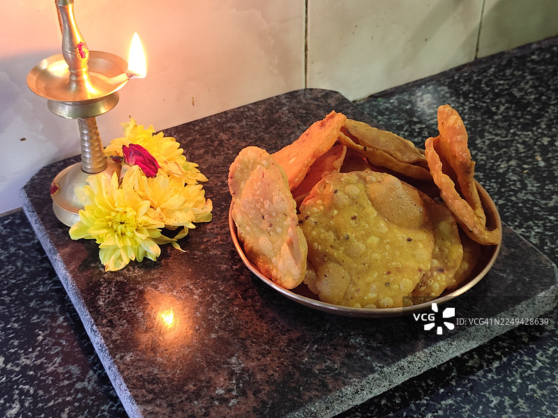 花岗岩柜台上摆放着传统的印度小吃和点亮的油灯，象征着庆祝和节日气氛图片素材
