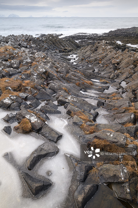 冰岛卡尔夫沙马尔维克，阴云密布的天空下，崎岖的海滩呈现出戏剧性的航拍景象，海滩上散布着独特的玄武岩柱和冰块图片素材
