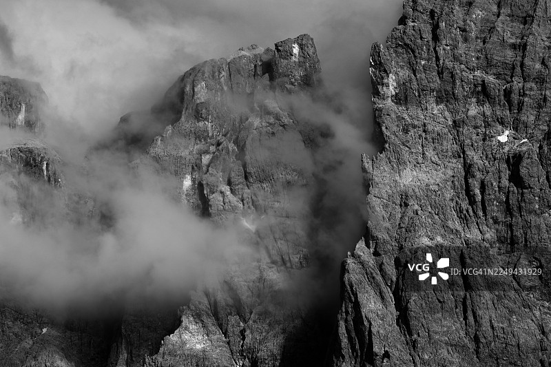 崎岖山峰的戏剧性黑白全景，笼罩在大气云雾中，强调大自然的原始力量和神秘感图片素材