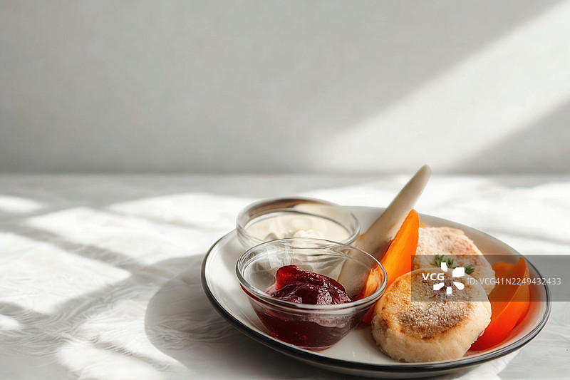 白盘子盛着美味的俄式奶酪松饼（Syrniki），配上新鲜柿子、果酱和酸奶油，是早餐或甜点的完美选择图片素材