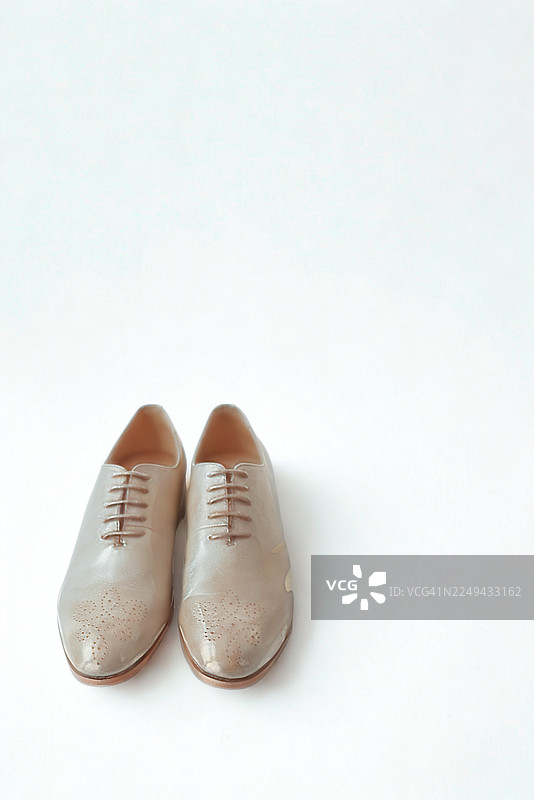 一双优雅的米色牛津鞋，细节精致，背景为纯白色，采用俯视角度拍摄图片素材