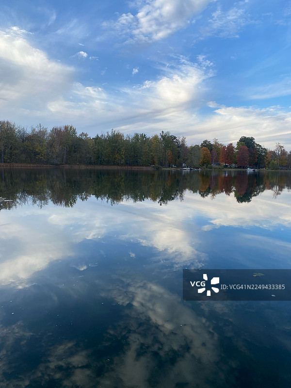宁静的秋日湖泊倒映着蓝天和五彩斑斓的树木，展现出宁静的自然和季节之美，马歇尔，美国图片素材