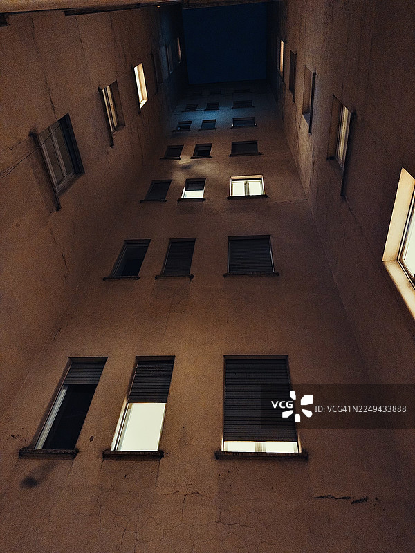 夜间仰视罗马意大利安东尼奥·托斯卡尼街道高楼，窗户灯火通明，天空黑暗图片素材