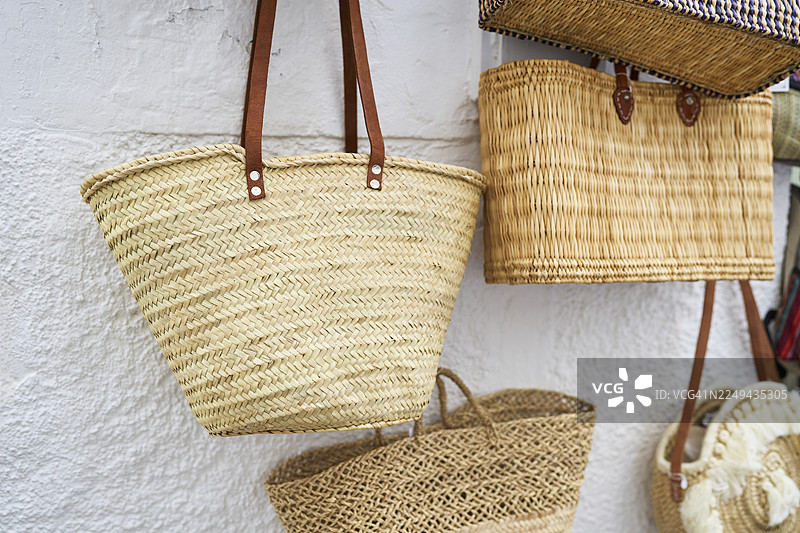手工编织草编包悬挂在有纹理的墙壁上图片素材
