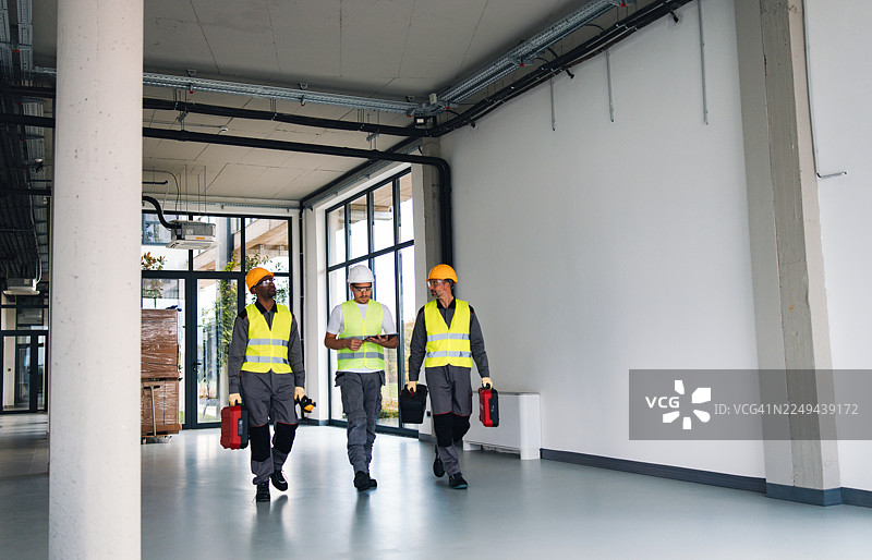 穿着高可视度服装、携带工具的建筑团队正在参观新的办公空间图片素材