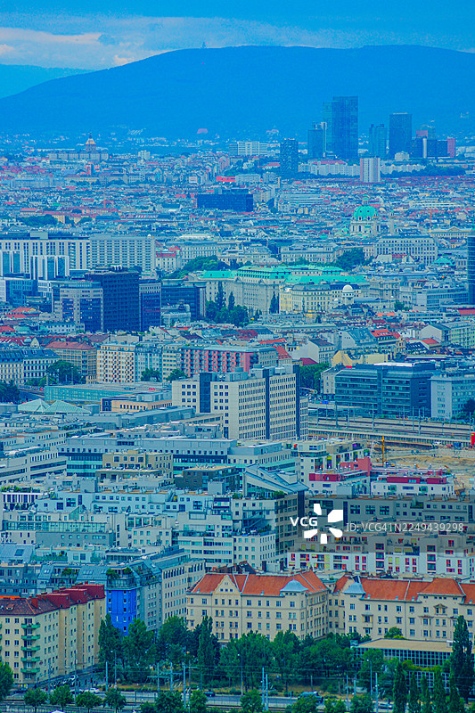 俯瞰奥地利维也纳广阔的城市景观，远方有山，天空多云图片素材