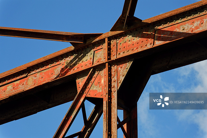 从低角度拍摄的生锈的红金属桥结构，背景是带有淡淡云彩的湛蓝天空，布拉格，捷克共和国图片素材
