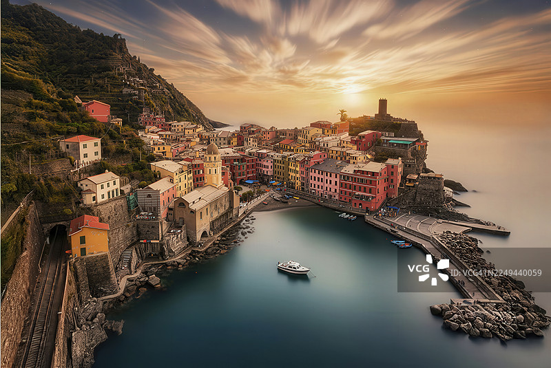 意大利五渔村韦尔纳扎的高角度景观，色彩斑斓的建筑依偎在海边，背景是壮丽的日落天空，韦尔纳扎，意大利图片素材