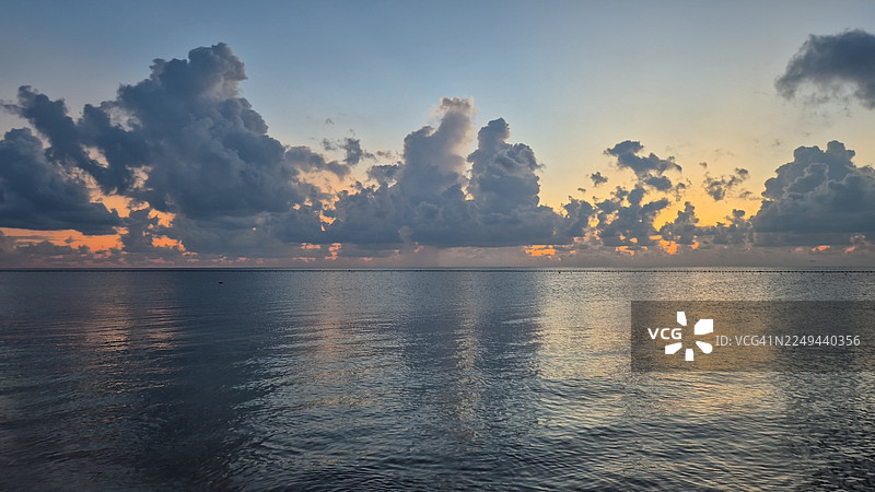 宁静的日落，平静的海面，戏剧性的云彩倒映在水中图片素材
