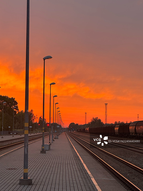 日落时分，火车站空荡荡的铁轨映衬着鲜艳的橙色天空图片素材