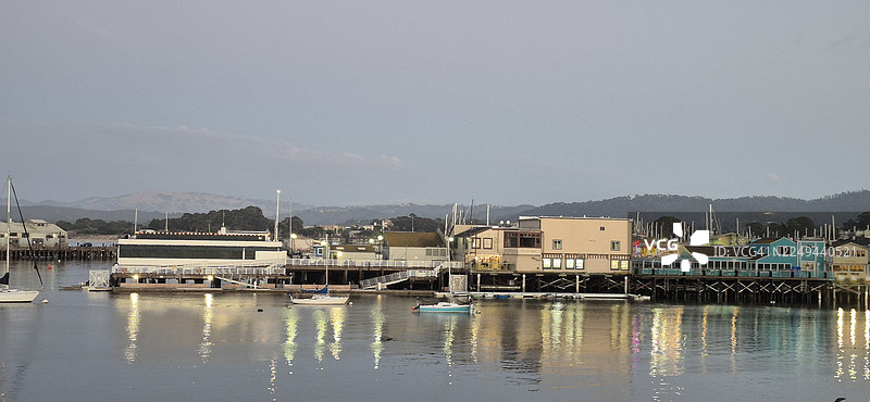 黄昏时分蒙特雷县湖泊的风景，建筑灯火通明，船只倒映在水面上，美国图片素材