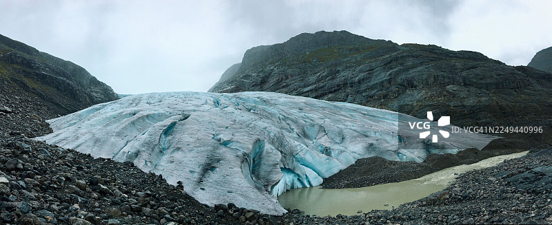 挪威孙菲尤尔地区，壮丽的冰川蜿蜒穿过崎岖的山地，天空多云，构成全景视野。图片素材