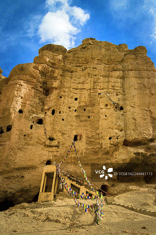 尼泊尔木斯塘洛曼塘，古老洞穴居所雕刻在岩石悬崖下，天空湛蓝图片素材