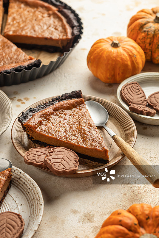 餐桌上摆放着美味的南瓜派切片、装饰性的叶子饼干和迷你南瓜，非常适合秋季庆典。图片素材