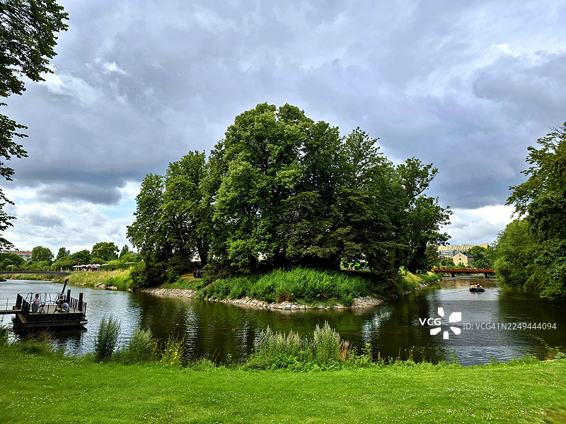 瑞典宁静的自然风光，碧绿的树木环绕着宁静的湖泊，天空布满戏剧性的云彩。图片素材