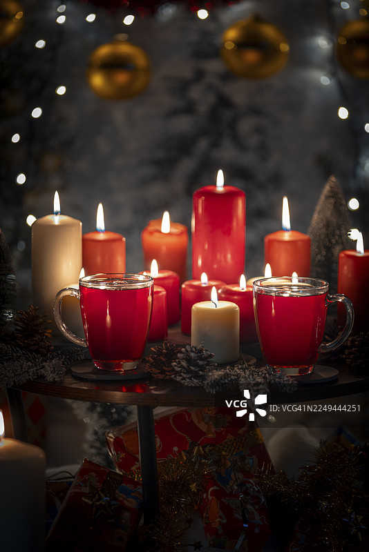 桌上摆放着红白蜡烛和杯子，背景是圣诞装饰图片素材