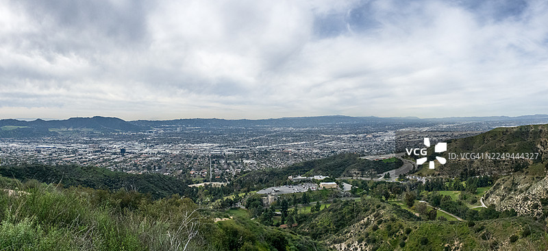俯瞰山丘环抱的广阔城镇，天空布满云彩，位于美国伯班克图片素材