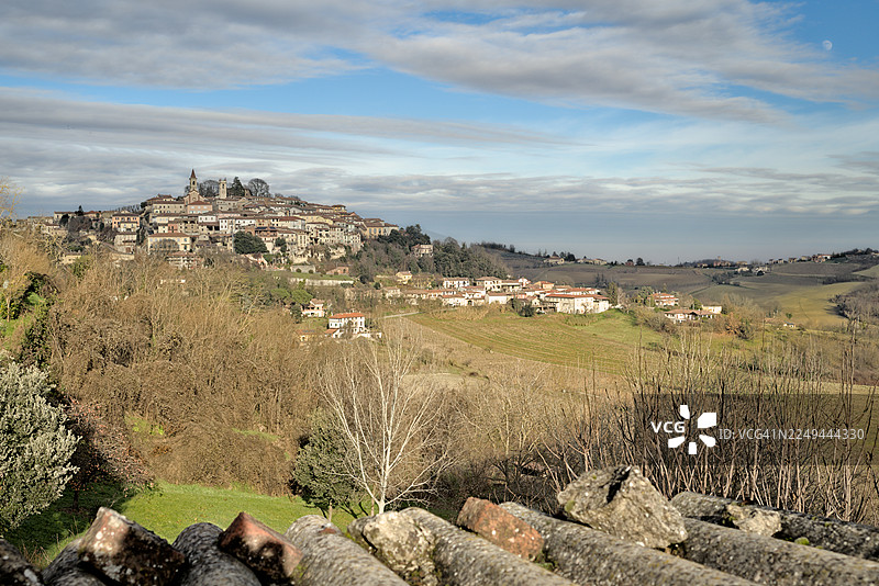 意大利罗西尼亚诺蒙费拉托，俯瞰山顶风景如画的村庄，周围环绕着连绵起伏的丘陵和葡萄园，天空多云图片素材