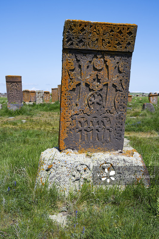 绿意盎然的风景中，一座带有复杂图案和橙色铜绿的墓碑，十字架石，哈奇卡石，世界上最大的哈奇卡石阵，诺拉图斯公墓，格加尔库尼克省，亚美尼亚图片素材