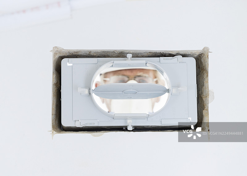 近距离拍摄一名建筑工人在安装过程中查看通风系统组件。图片素材