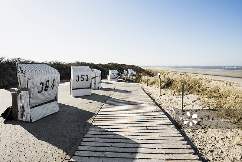 冬季海滩沙丘上的椅子和蓝天，德国下萨克森州东弗里西亚群岛的斯皮克罗格图片素材