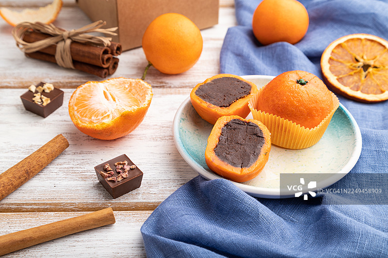 白木背景和蓝色亚麻织物上的松露巧克力橘子糖果。侧视图，特写图片素材
