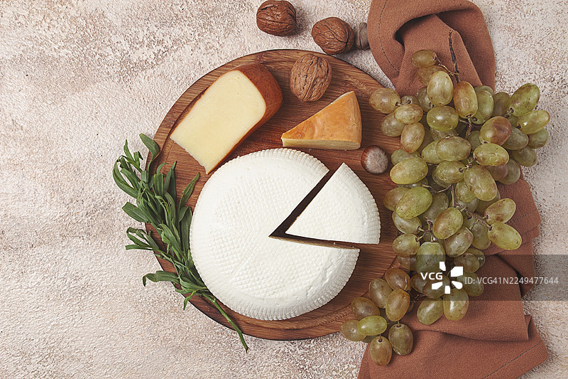 奶酪、伊梅列季奶酪和熏苏鲁古尼奶酪、葡萄、坚果，放在砧板上，格鲁吉亚美食，无人图片素材