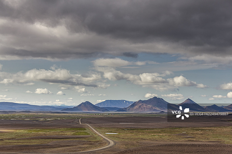 冰岛北部莫兹鲁达勒的夏季，一片荒芜的火山地貌，一条碎石路，云层图片素材
