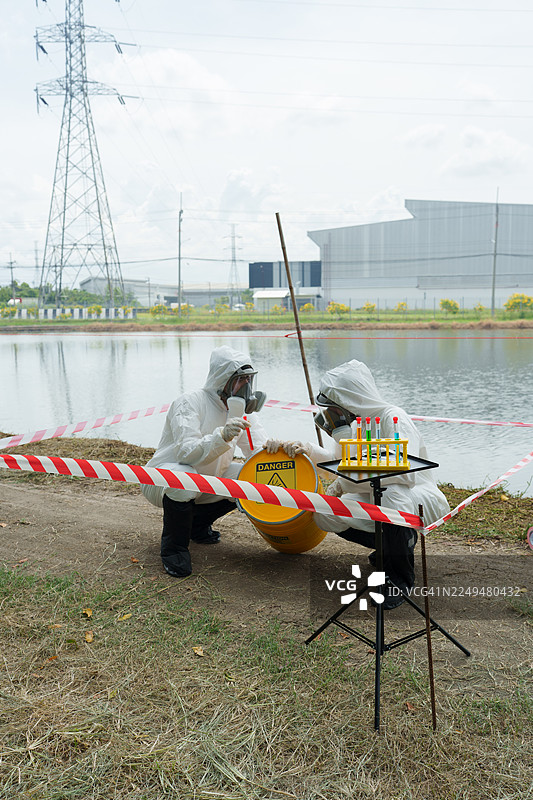 生态学家身着防护服，在养殖水生动物的农场池塘中检查水质，并采集水样进行分析。图片素材