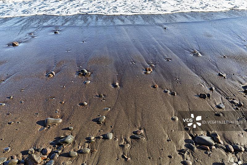 黑色熔岩海滩上的卵石，海滨，普拉卡马达，亚伊萨，兰萨罗特，西班牙图片素材