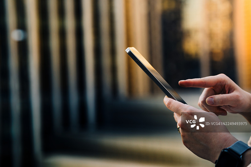 特写女性用智能手机处理日常银行业务，通过在线银行手机应用，背景为城市景观。可以快速便捷地在线访问和管理账户。数字银行。电子银行管理。科技赋能的财富管理。图片素材