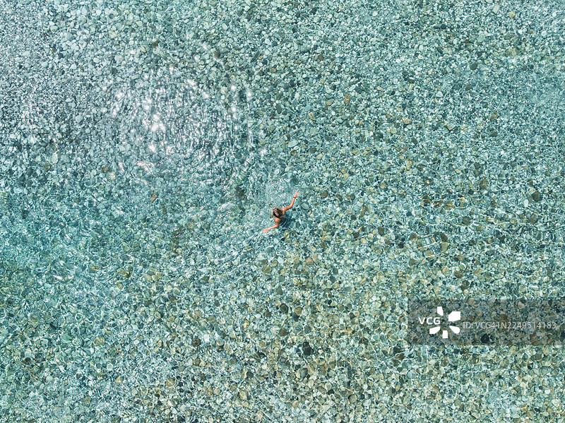 无人机照片显示一名女子站在阿尔巴尼亚斯库台县的浅河水中图片素材