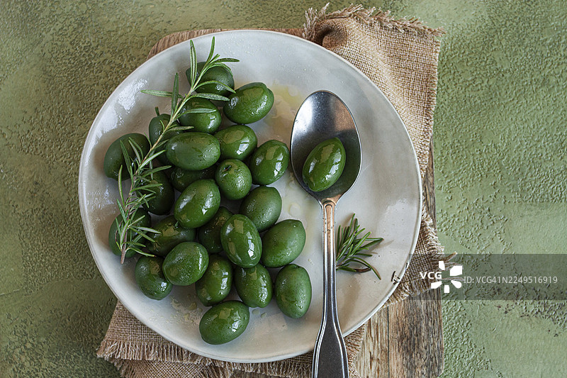 希腊哈尔基迪基橄榄，经典的希腊绿橄榄，放在盘子里，配有勺子，俯视角度，无人物图片素材