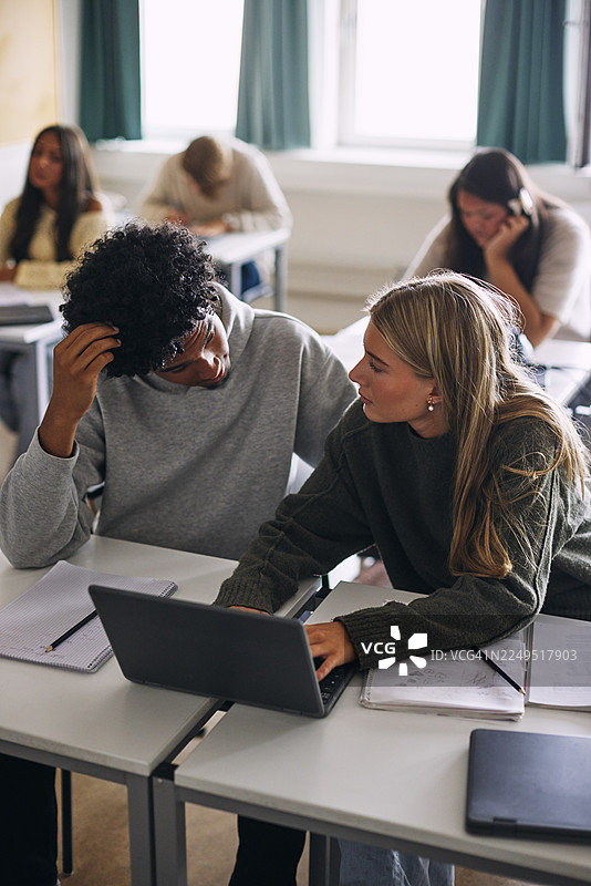 从高处俯瞰，一群男女朋友在学校教室里一起用笔记本电脑学习图片素材
