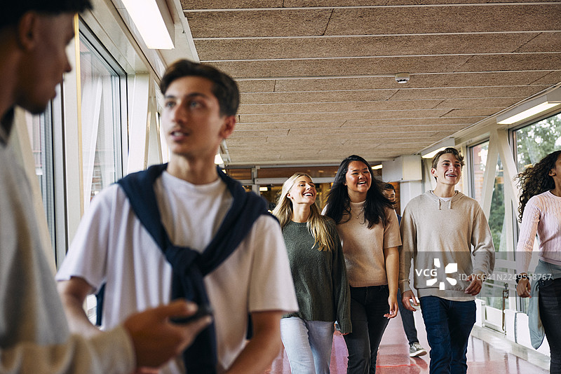 快乐的男女同学们在高中走廊里行走图片素材