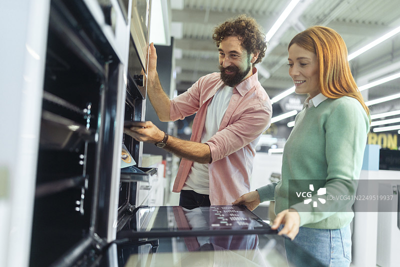 夫妻俩在电器商店选购嵌入式烤箱，黑色星期五购物季，他们正做出购买决定图片素材
