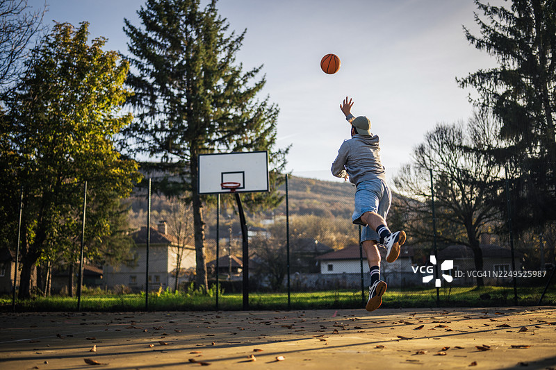 中年男性在街头篮球场上玩耍，享受乐趣。图片素材
