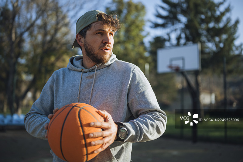 日落时分，街头篮球场上的一位男性篮球运动员肖像。图片素材