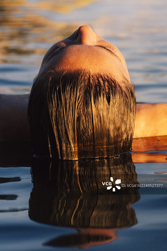 黎明时分，女子在湖中无忧无虑地游泳图片素材