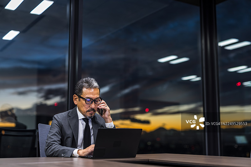 公司高管晚上独自一人在会议室里。图片素材