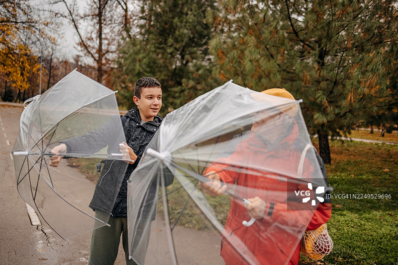 一位老人与他的孙子在雨天的公园里见面，并撑开雨伞图片素材