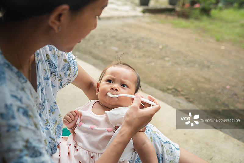 婴儿坐在腿上在户外喂食图片素材