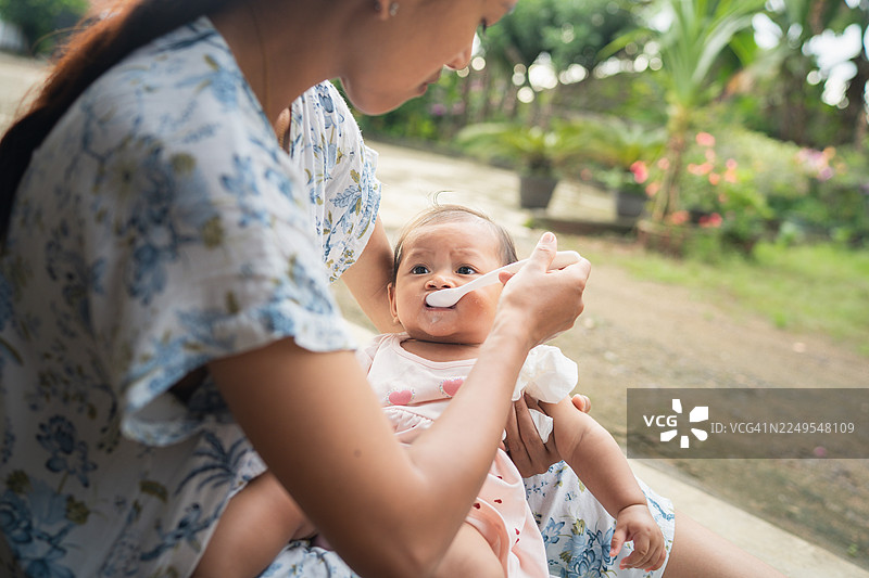 宝宝坐在腿上在户外被喂食图片素材