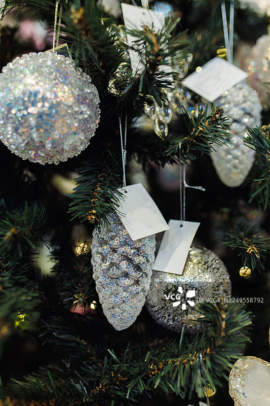 银色闪光装饰品挂在圣诞树上，配有白色标签和柔和的灯光图片素材